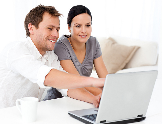 Cute man showing something on the laptop screen to his girlfriend